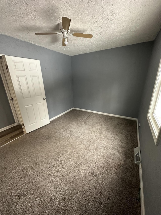 empty room featuring a textured ceiling, ceiling fan, and carpet