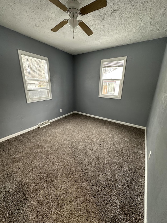 empty room featuring ceiling fan, carpet, and a textured ceiling