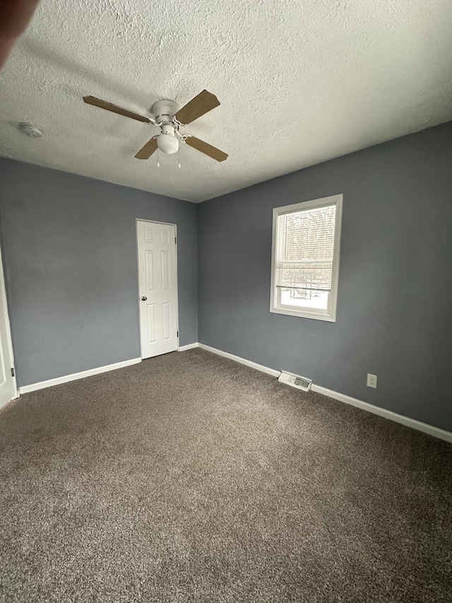 empty room with a textured ceiling, carpet floors, and ceiling fan