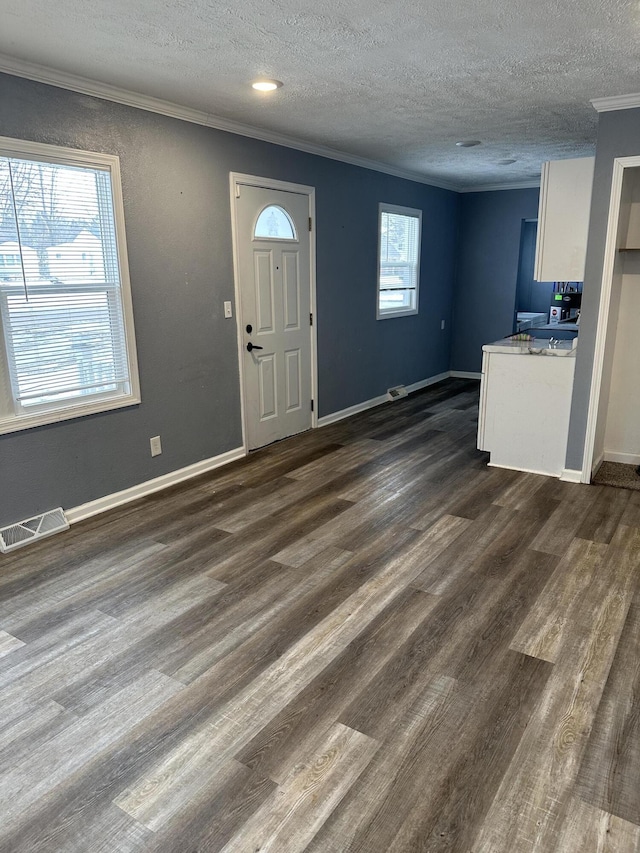 entrance foyer featuring ornamental molding, dark wood-type flooring, and a textured ceiling