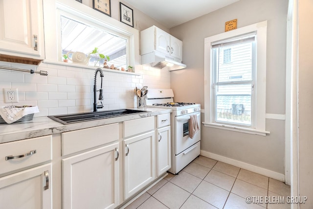 kitchen with sink, white gas stove, white cabinetry, tasteful backsplash, and light tile patterned floors