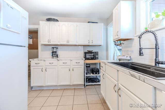 kitchen with sink, light tile patterned floors, white fridge, white cabinets, and backsplash