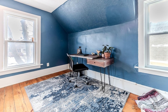 office area with lofted ceiling, hardwood / wood-style floors, a textured ceiling, and a wealth of natural light