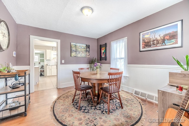 dining space featuring light hardwood / wood-style floors and a textured ceiling