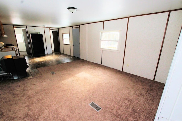 unfurnished bedroom featuring black refrigerator and dark carpet