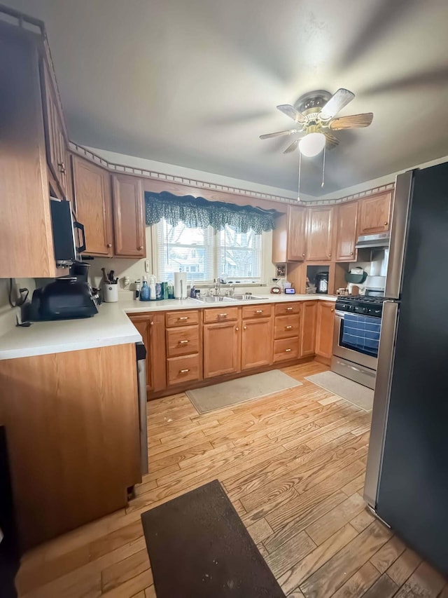 kitchen with ceiling fan, appliances with stainless steel finishes, sink, and light hardwood / wood-style flooring