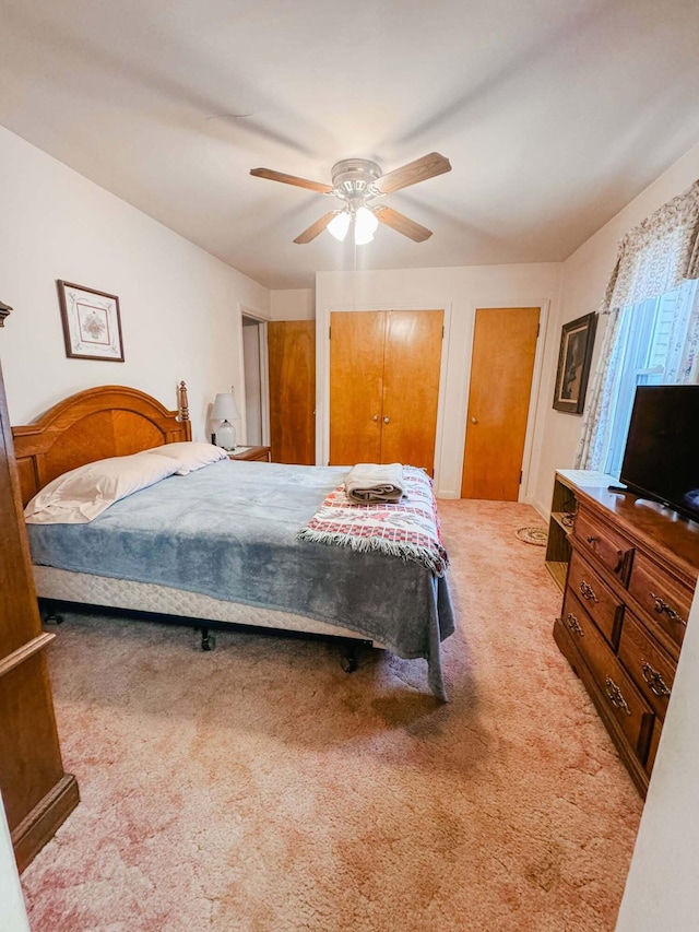 carpeted bedroom with two closets and ceiling fan