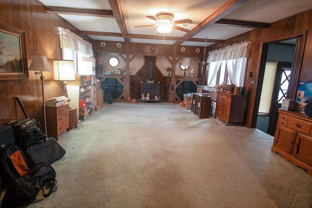 interior space with light carpet, wooden walls, beamed ceiling, and a wood stove