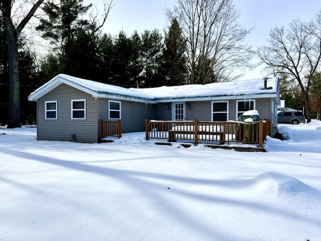 snow covered back of property with a wooden deck