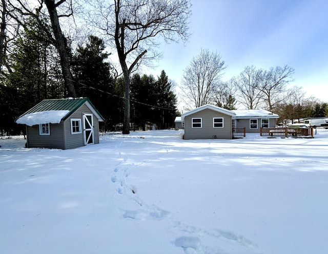 yard covered in snow featuring a wooden deck and an outdoor structure