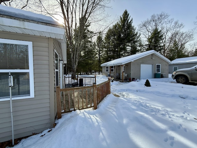 view of snowy exterior with a garage and an outbuilding