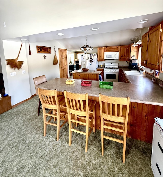 kitchen with pendant lighting, sink, white appliances, dark carpet, and kitchen peninsula