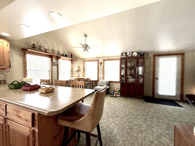 kitchen with ceiling fan, lofted ceiling, a breakfast bar area, and carpet