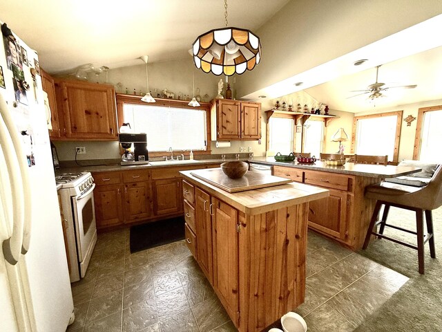 kitchen featuring decorative light fixtures, vaulted ceiling, a kitchen breakfast bar, a kitchen island, and white appliances