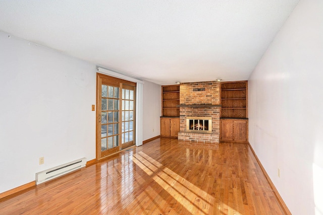 unfurnished living room featuring a brick fireplace, built in shelves, wood-type flooring, and baseboard heating