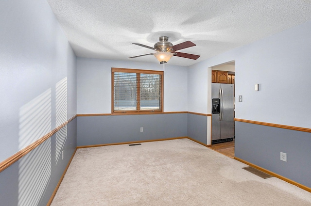 carpeted spare room featuring a textured ceiling and ceiling fan