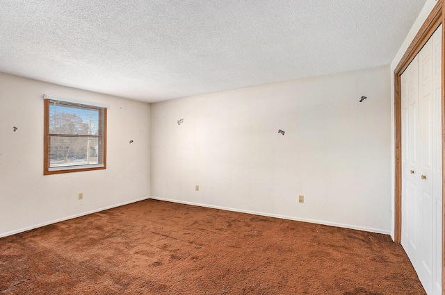 spare room with dark colored carpet and a textured ceiling