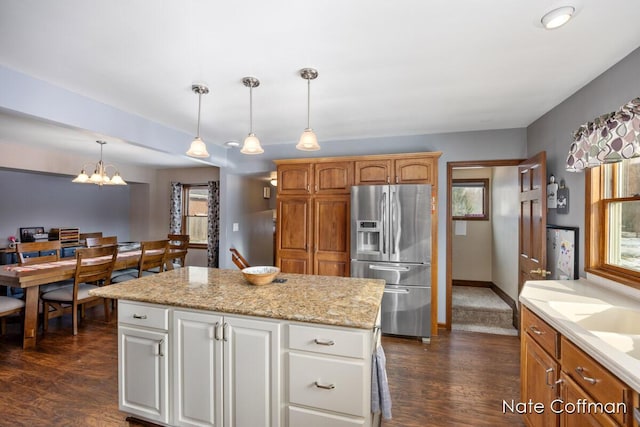 kitchen featuring white cabinetry, stainless steel fridge with ice dispenser, hanging light fixtures, and a kitchen island