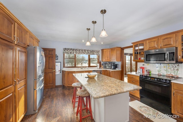 kitchen featuring a kitchen island, appliances with stainless steel finishes, a breakfast bar area, backsplash, and dark wood-type flooring