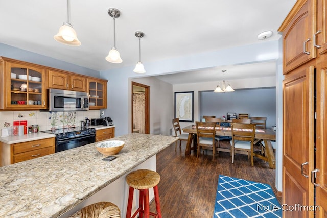 kitchen featuring dark hardwood / wood-style flooring, black range with electric stovetop, hanging light fixtures, and a kitchen bar