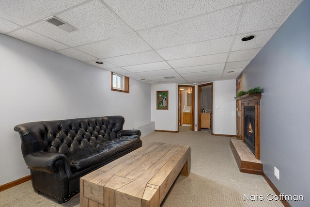 living room with a paneled ceiling and light colored carpet