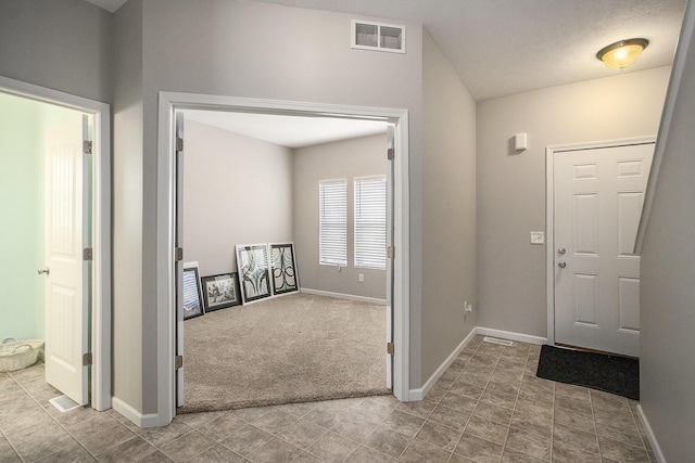 carpeted entryway featuring lofted ceiling