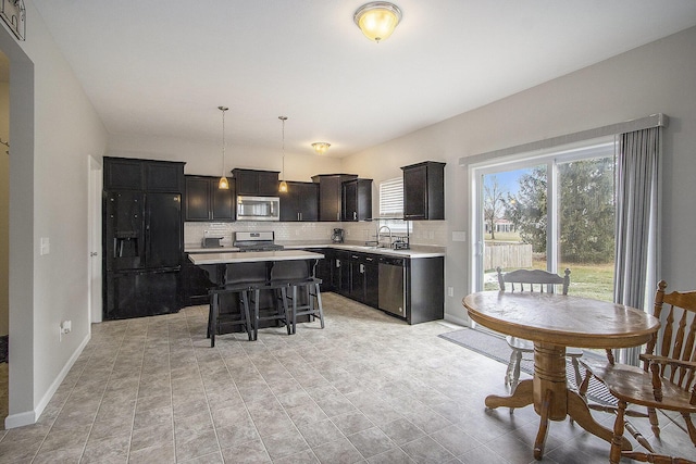 kitchen with pendant lighting, a breakfast bar, backsplash, stainless steel appliances, and a kitchen island