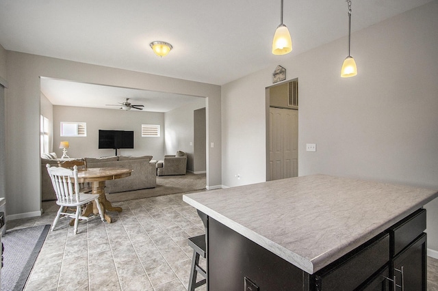 kitchen with ceiling fan, a kitchen bar, a center island, and hanging light fixtures