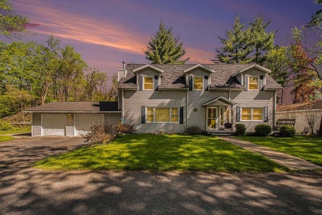 cape cod-style house with a garage and a lawn