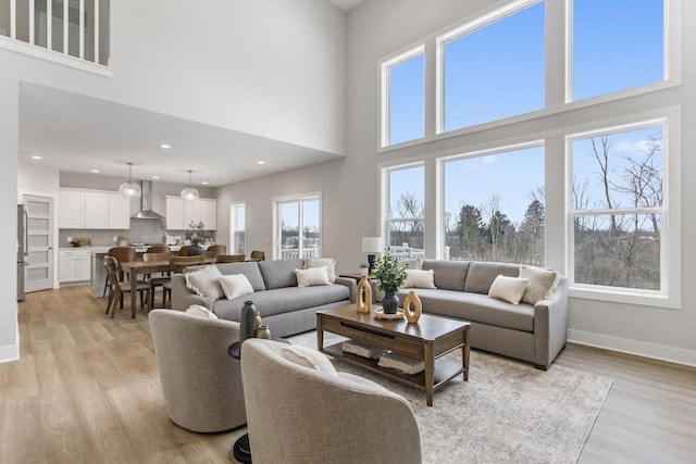 living room featuring a towering ceiling and light wood-type flooring