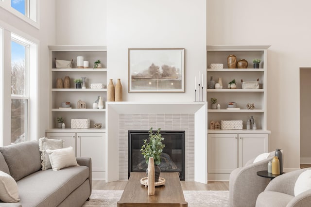 living room with a tiled fireplace and light hardwood / wood-style flooring