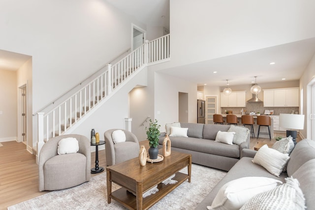 living room with a towering ceiling and light wood-type flooring