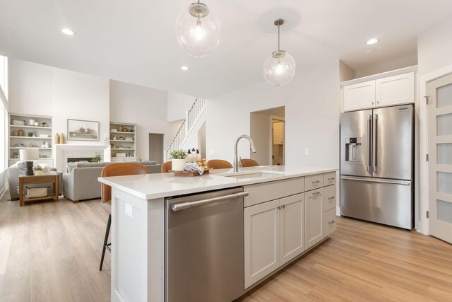 kitchen with sink, white cabinetry, an island with sink, pendant lighting, and stainless steel appliances