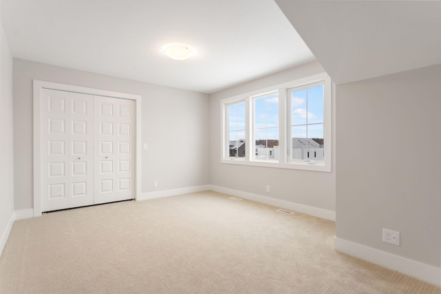 unfurnished bedroom featuring light carpet and a closet