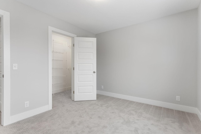 unfurnished bedroom with a closet, a spacious closet, and light carpet