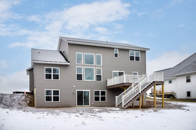 snow covered back of property with a wooden deck