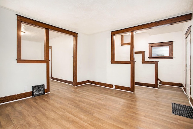 spare room with a textured ceiling and light wood-type flooring