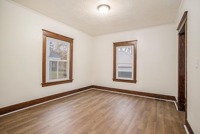 empty room with ornamental molding, dark wood-type flooring, and a textured ceiling