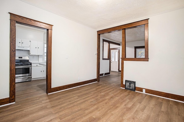 empty room with crown molding, a textured ceiling, and light hardwood / wood-style floors