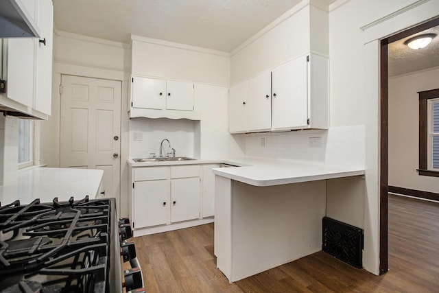 kitchen featuring sink, wood-type flooring, kitchen peninsula, and white cabinets