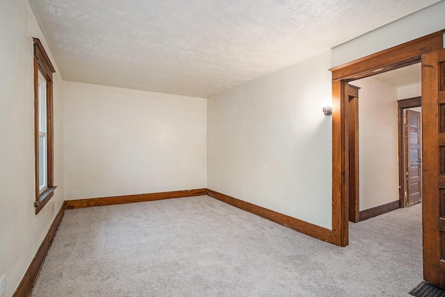 empty room featuring light colored carpet and a textured ceiling