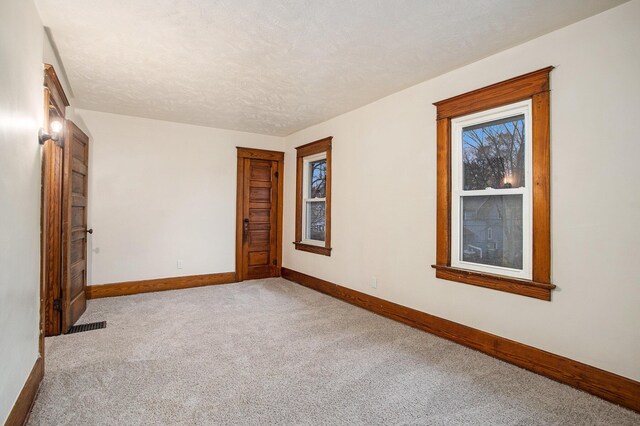 empty room with carpet and a textured ceiling