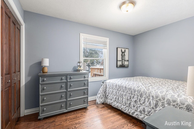 bedroom with dark wood-type flooring, a textured ceiling, and a closet