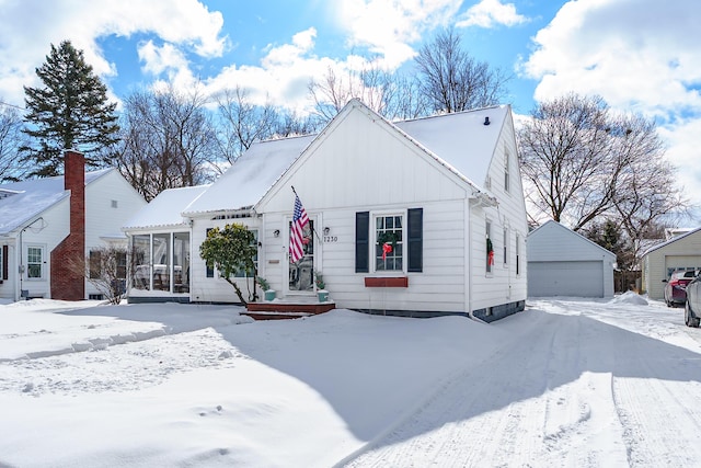 view of front of property with board and batten siding, a sunroom, an outdoor structure, and a detached garage