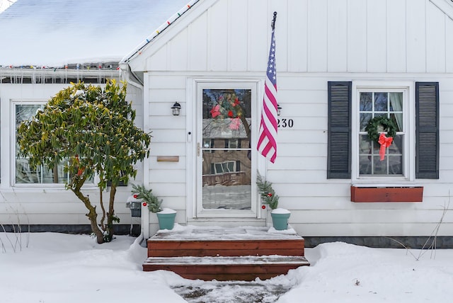 snow covered property entrance with board and batten siding