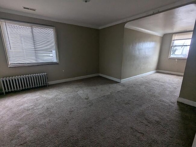 spare room with carpet floors, radiator, and crown molding