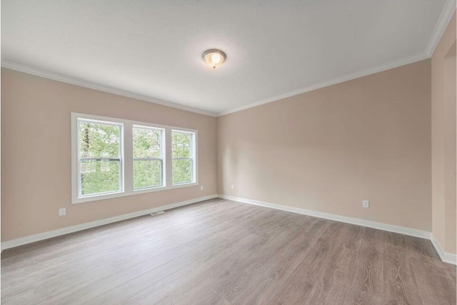 empty room with ornamental molding and light hardwood / wood-style floors