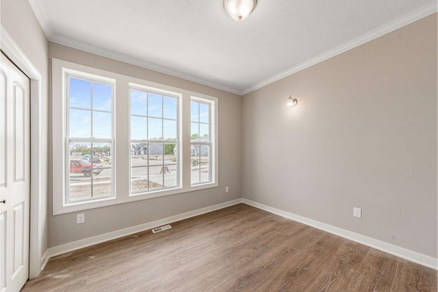 spare room with ornamental molding and wood-type flooring