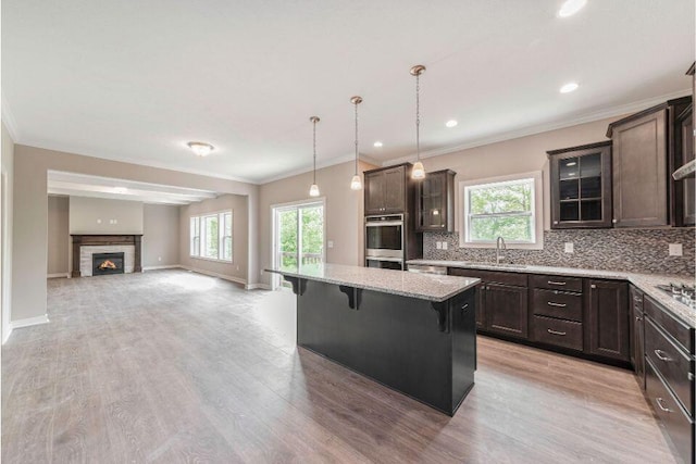 kitchen with sink, a breakfast bar area, tasteful backsplash, decorative light fixtures, and a kitchen island