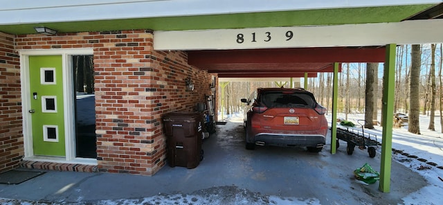 snow covered garage featuring a carport